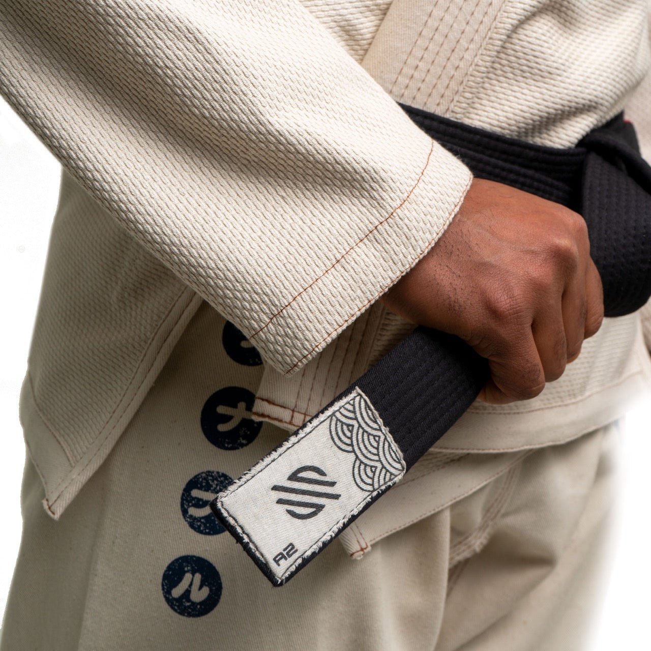 Person holding a martial arts black belt in a beige gi.